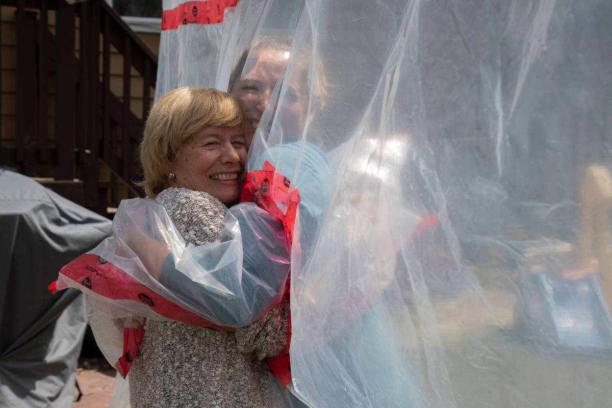 O abraço através do plástico pendurado no varal, no Canadá (Foto: AFP)